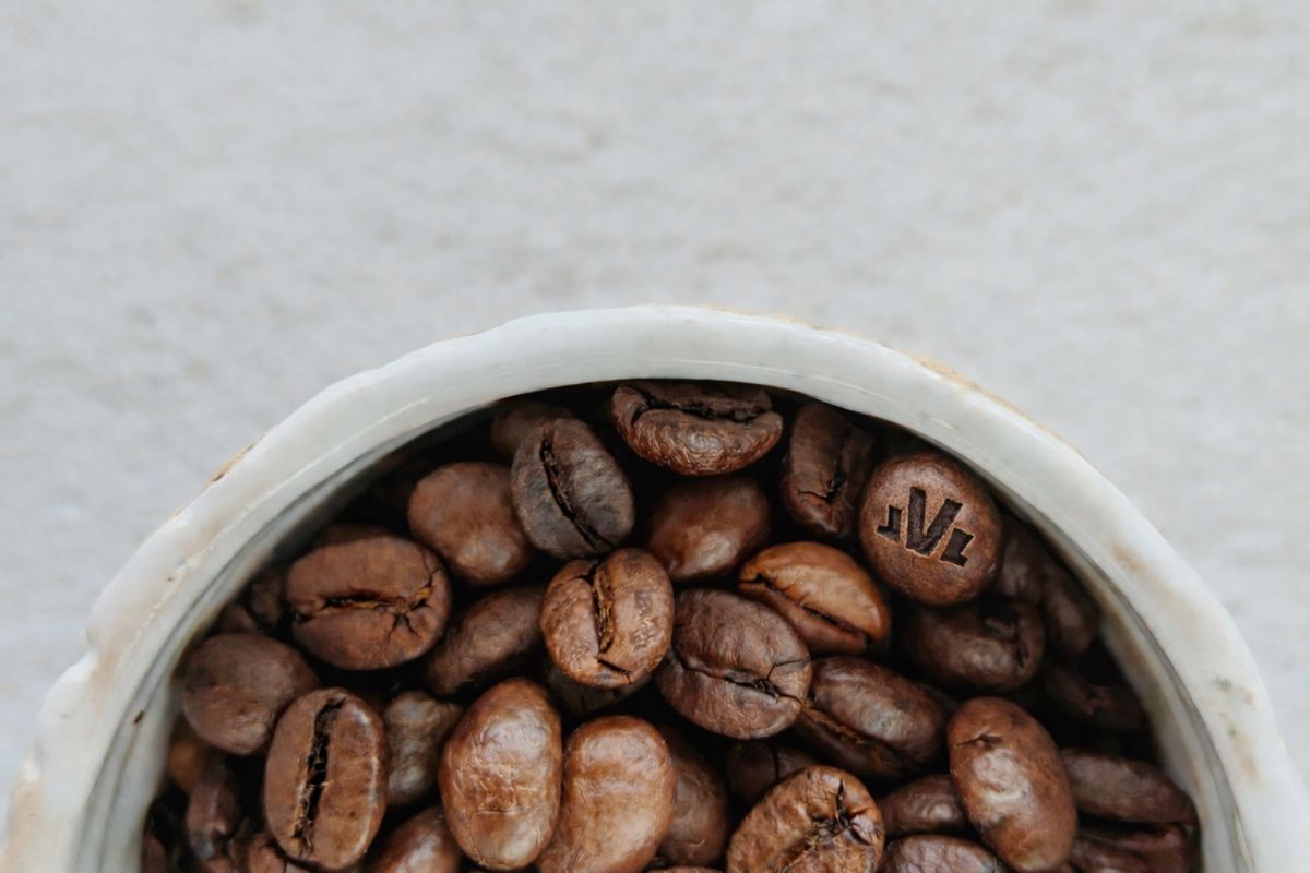 Coffee beans in a cup up close with engraved The Fifth logo on bean